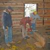 With the logs hewed down as seen on the interior wall in back ground, Kevin oversees the dovetailing of a veneer log. 