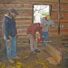 With the logs hewed down as seen on the interior wall in back ground, Kevin oversees the dovetailing of a veneer log. 